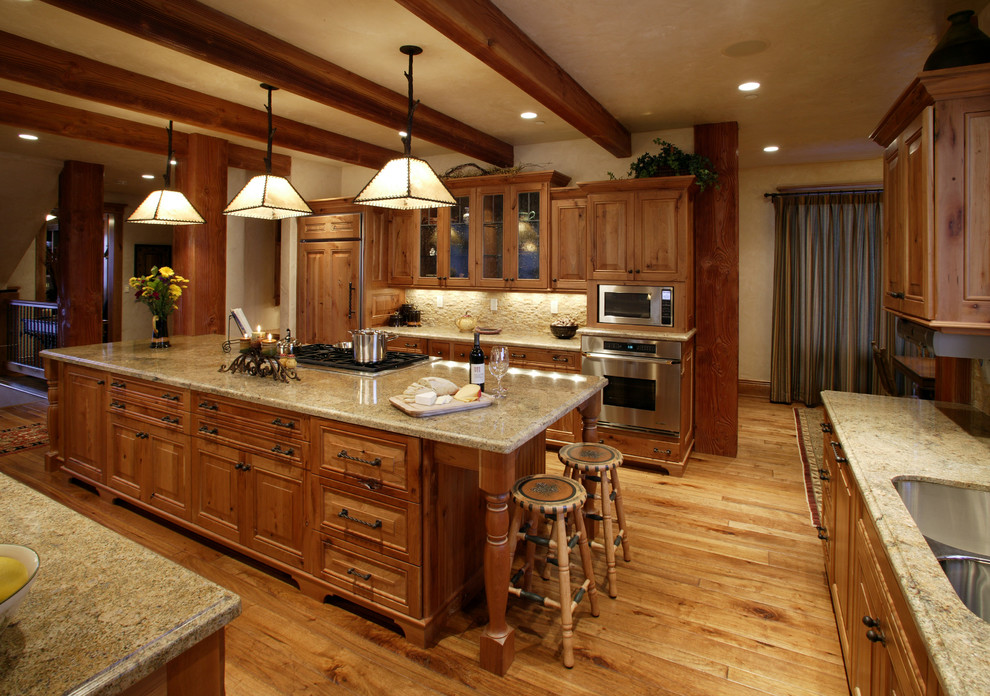 This is an example of a large country u-shaped eat-in kitchen in Denver with a double-bowl sink, shaker cabinets, medium wood cabinets, granite benchtops, stainless steel appliances, light hardwood floors and with island.