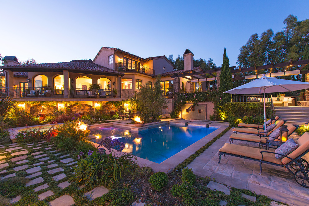 Inspiration for a mediterranean l-shaped pool in Los Angeles with natural stone pavers.