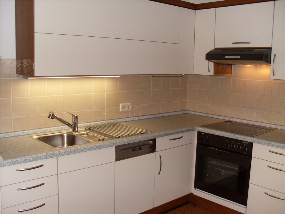 Photo of a medium sized traditional l-shaped kitchen/diner in Other with a built-in sink, flat-panel cabinets, beige cabinets, laminate countertops, beige splashback, ceramic splashback and coloured appliances.
