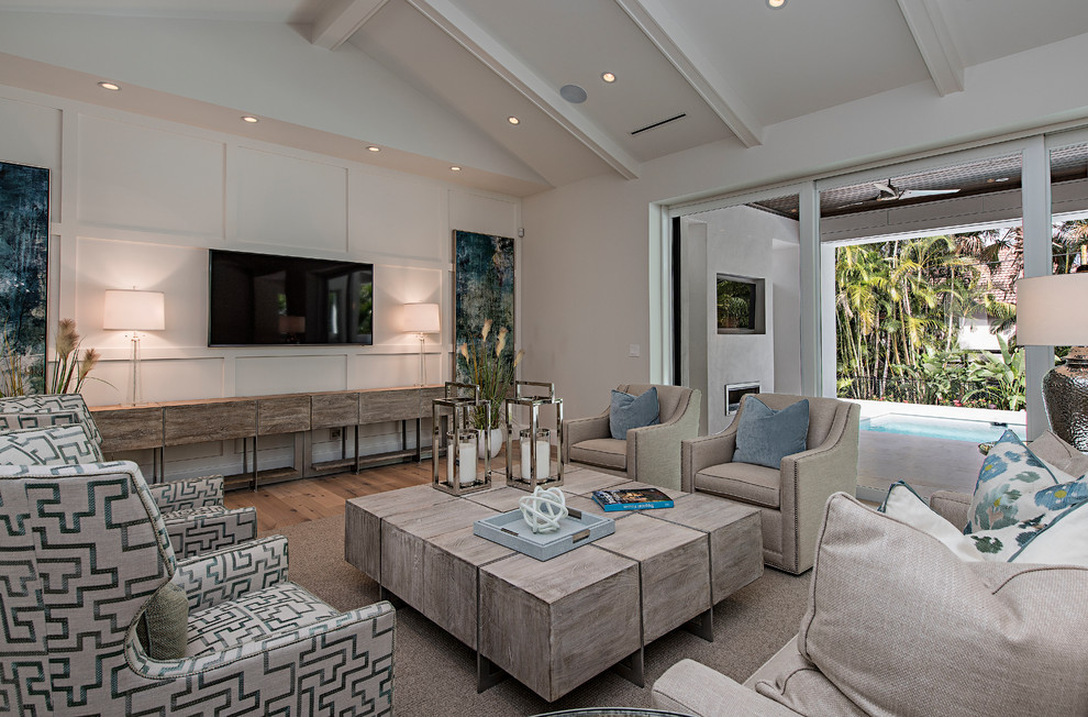 Beach style family room in Miami with grey walls, medium hardwood floors, no fireplace, a wall-mounted tv and brown floor.