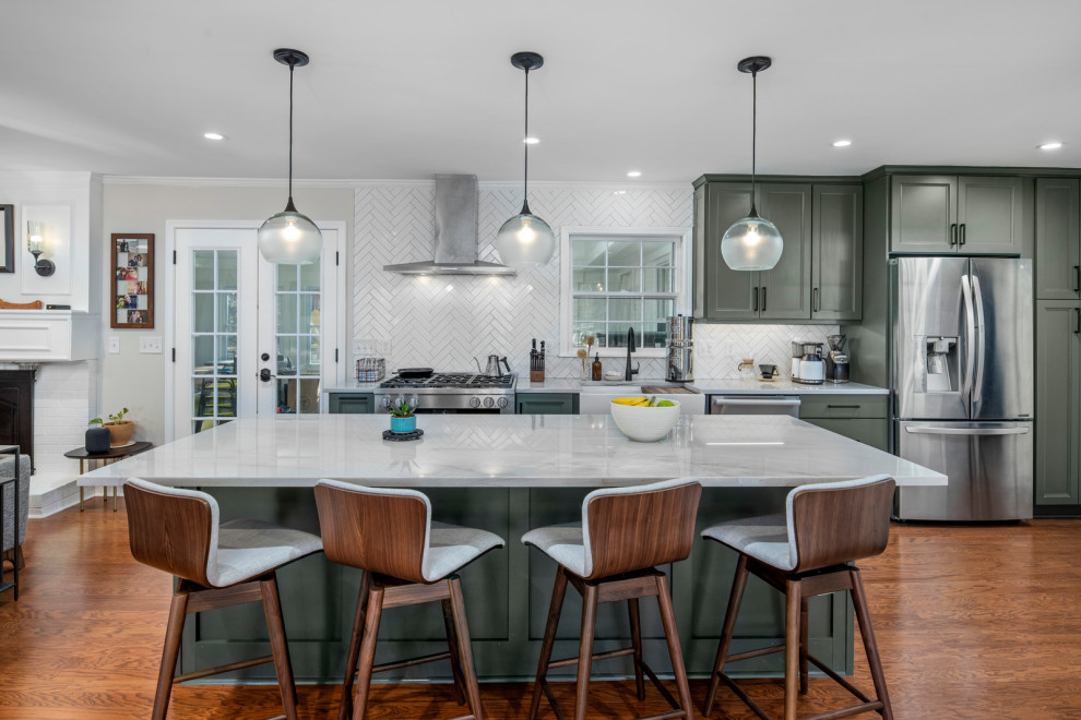 Photo of a large midcentury l-shaped open plan kitchen in Atlanta with a farmhouse sink, shaker cabinets, green cabinets, quartzite benchtops, white splashback, subway tile splashback, stainless steel appliances, dark hardwood floors, with island, brown floor and grey benchtop.