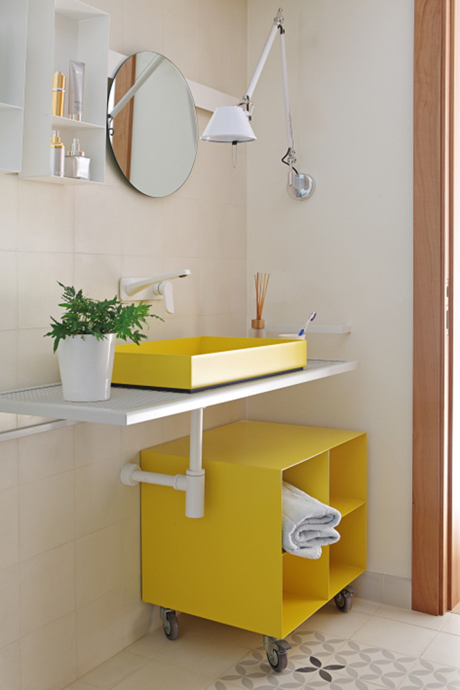 Photo of a small contemporary powder room in Valencia with beige tile, ceramic tile, beige walls, mosaic tile floors, a vessel sink, stainless steel benchtops, yellow cabinets and open cabinets.