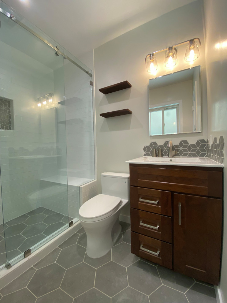 Design ideas for a mid-sized modern master bathroom in Los Angeles with shaker cabinets, dark wood cabinets, an open shower, a one-piece toilet, white tile, ceramic tile, grey walls, ceramic floors, a console sink, marble benchtops, grey floor, a sliding shower screen, white benchtops, a niche, a single vanity and a built-in vanity.