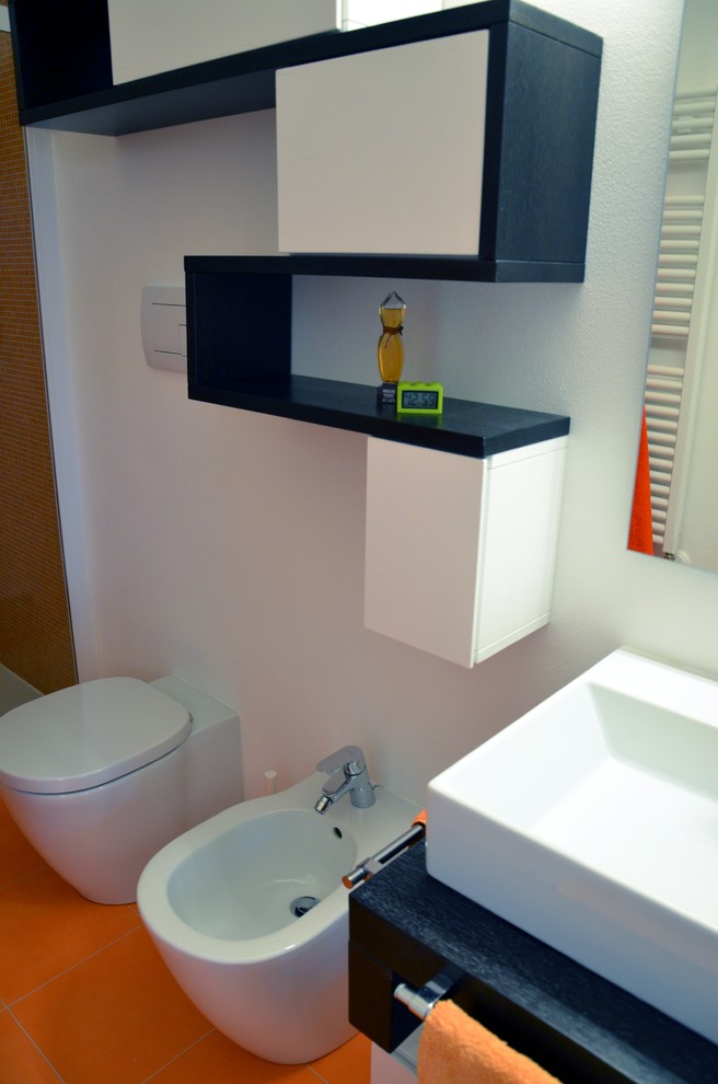 Small modern 3/4 bathroom in Milan with flat-panel cabinets, medium wood cabinets, a double shower, a two-piece toilet, orange tile, porcelain tile, orange walls, porcelain floors, a vessel sink and wood benchtops.