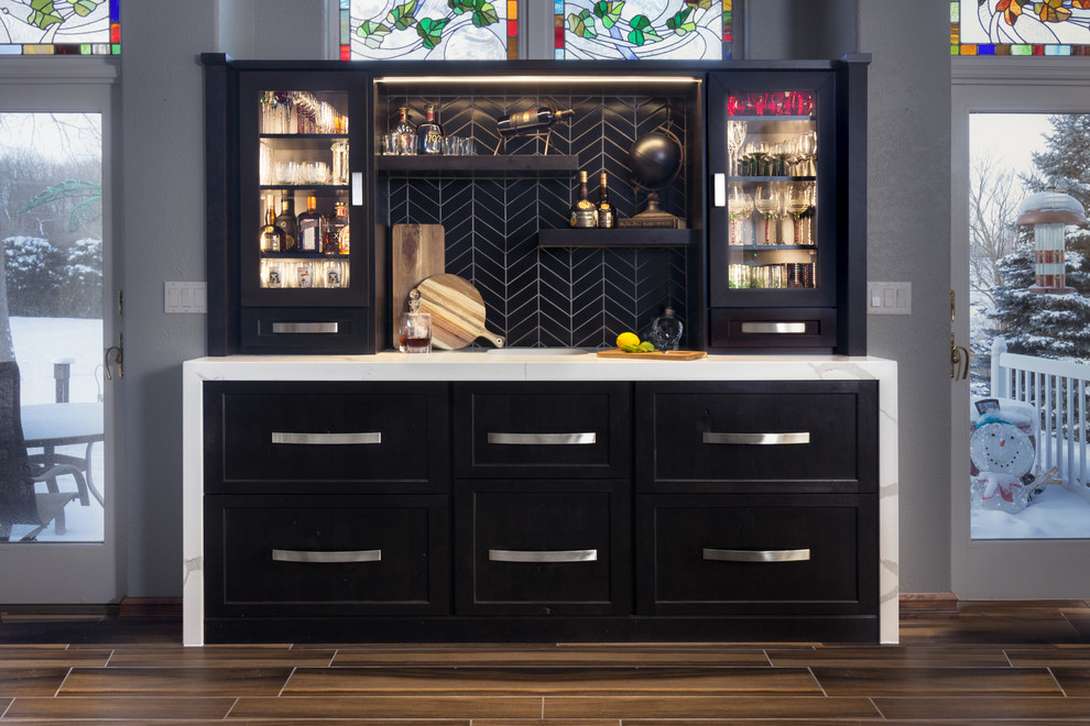 Inspiration for a small contemporary galley wet bar in Other with an undermount sink, recessed-panel cabinets, black cabinets, quartz benchtops, black splashback, ceramic splashback, porcelain floors, brown floor and white benchtop.
