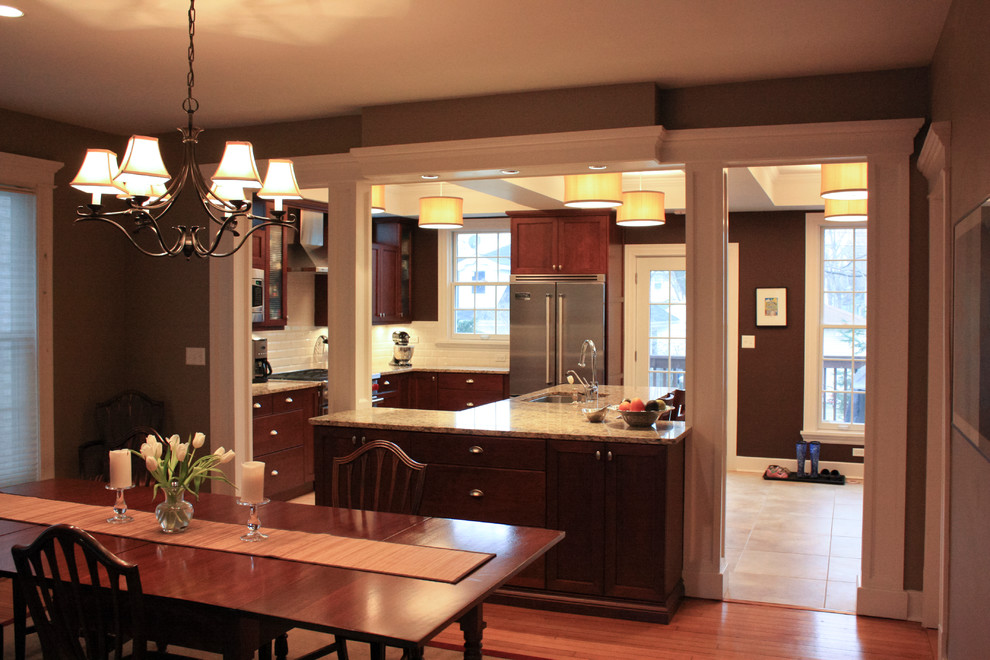 Example of a mid-sized transitional porcelain tile eat-in kitchen design in Chicago with an undermount sink, flat-panel cabinets, dark wood cabinets, granite countertops, white backsplash, porcelain backsplash, stainless steel appliances and an island
