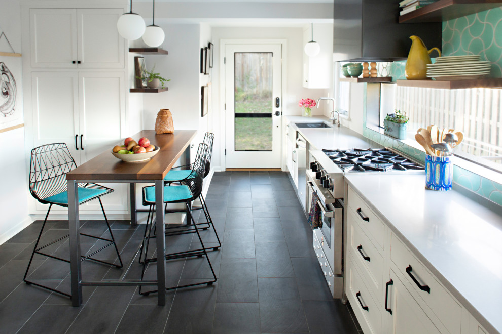 This is an example of a mid-sized transitional galley eat-in kitchen in DC Metro with a farmhouse sink, shaker cabinets, white cabinets, quartzite benchtops, green splashback, ceramic splashback, stainless steel appliances, slate floors, a peninsula, black floor, grey benchtop and exposed beam.