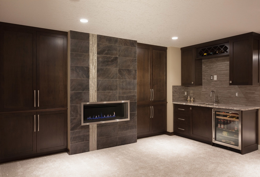 Design ideas for a large contemporary single-wall wet bar in Calgary with an undermount sink, recessed-panel cabinets, dark wood cabinets, granite benchtops, brown splashback, stone tile splashback and carpet.