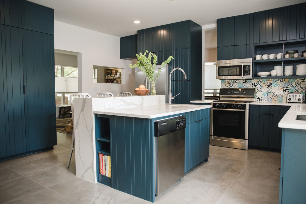 Mid-sized contemporary l-shaped open plan kitchen in Austin with an undermount sink, flat-panel cabinets, blue cabinets, quartz benchtops, multi-coloured splashback, cement tile splashback, stainless steel appliances, cement tiles, with island, grey floor and white benchtop.