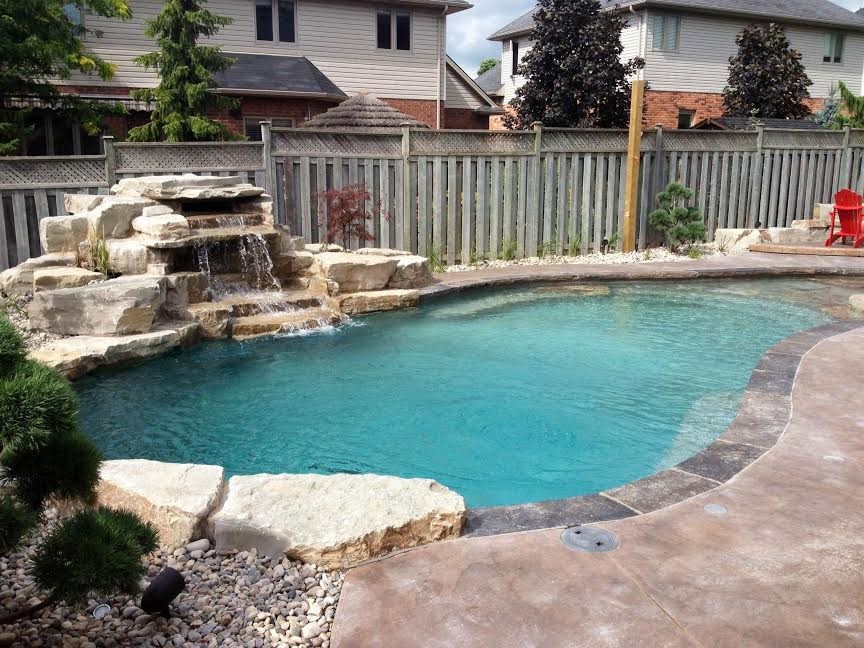 Inspiration for a mid-sized transitional backyard stamped concrete and custom-shaped natural pool fountain remodel in Toronto
