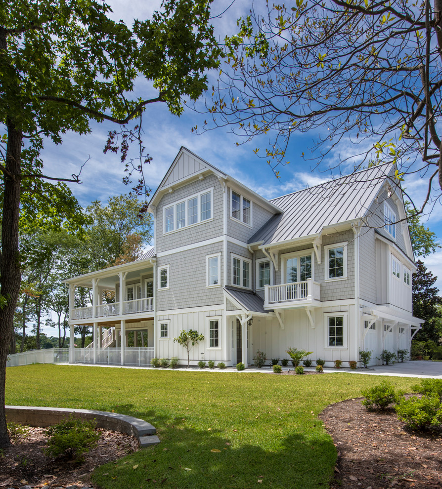 Large beach style three-storey grey house exterior in Wilmington with mixed siding, a gable roof and a metal roof.