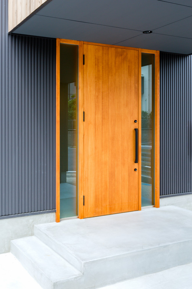 Стильный дизайн: входная дверь в современном стиле с черными стенами, бетонным полом, одностворчатой входной дверью, входной дверью из дерева среднего тона и серым полом - последний тренд