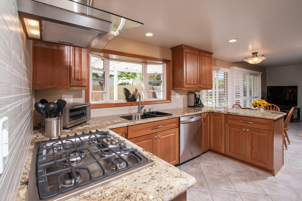 Mid-sized transitional u-shaped ceramic tile kitchen photo in San Diego with a double-bowl sink, raised-panel cabinets, medium tone wood cabinets, solid surface countertops, white backsplash, ceramic backsplash, stainless steel appliances and a peninsula