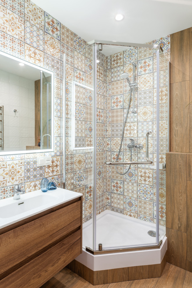 Пример оригинального дизайна: маленькая ванная комната в белых тонах с отделкой деревом в средиземноморском стиле с плоскими фасадами, светлыми деревянными фасадами, угловым душем, инсталляцией, разноцветной плиткой, керамической плиткой, полом из керамогранита, душевой кабиной, коричневым полом, душем с распашными дверями, белой столешницей, гигиеническим душем, тумбой под одну раковину и подвесной тумбой для на участке и в саду