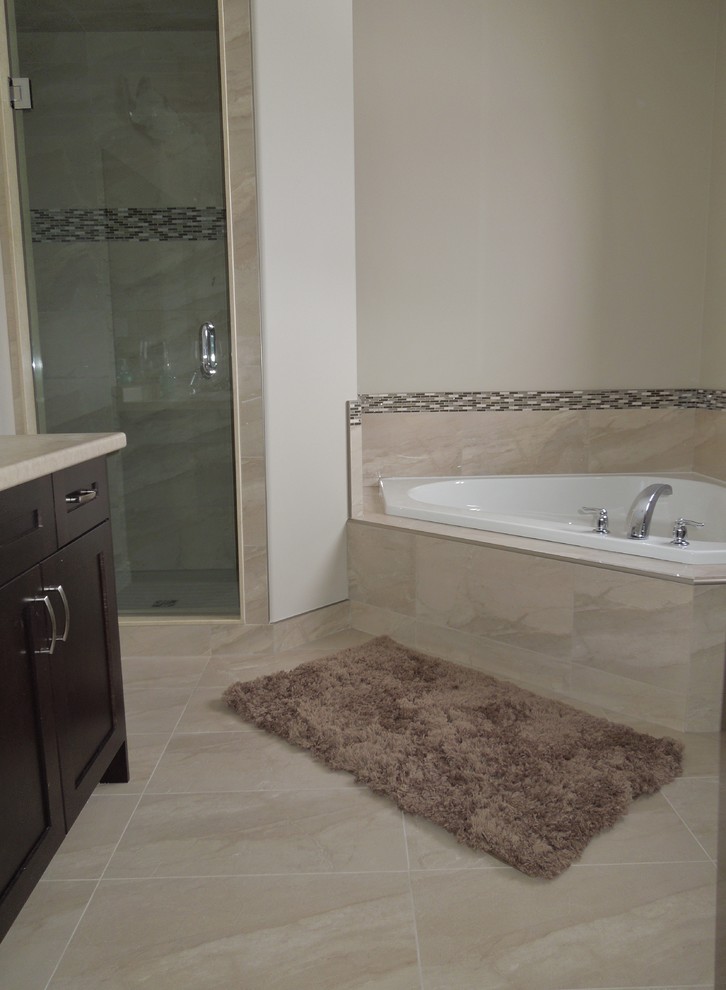 Photo of a transitional master bathroom in Toronto with shaker cabinets, dark wood cabinets, laminate benchtops, a corner tub, a corner shower, a one-piece toilet, beige tile, porcelain tile, beige walls and porcelain floors.