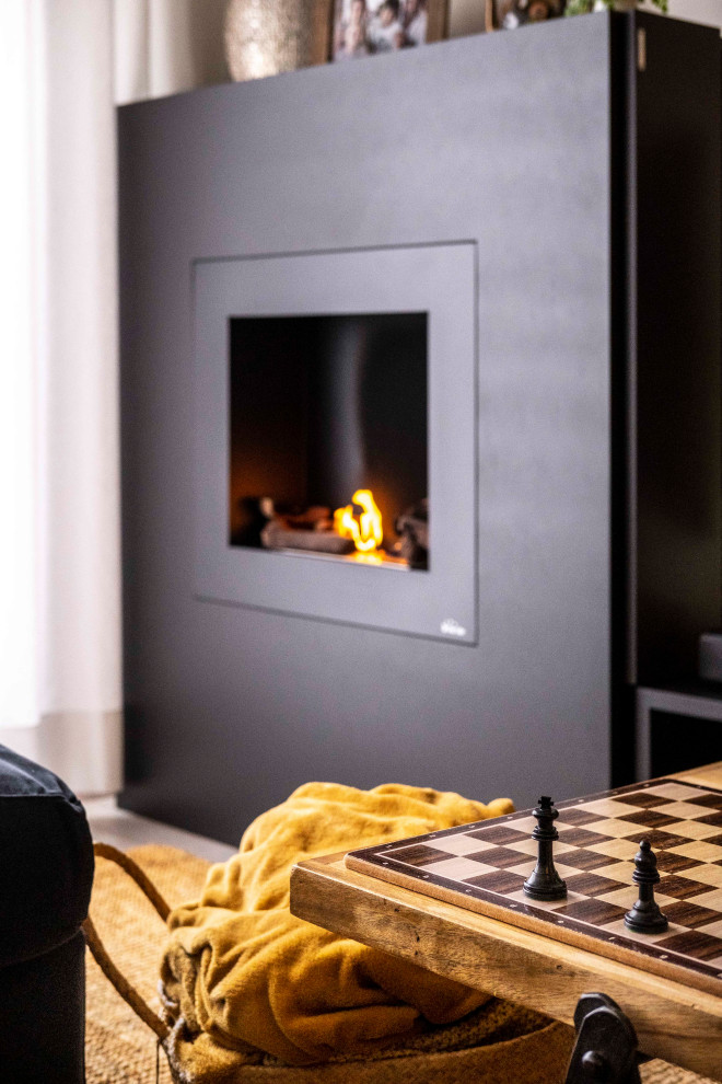 Ejemplo de sala de estar tipo loft industrial de tamaño medio con paredes blancas, suelo laminado, estufa de leña, marco de chimenea de metal, televisor retractable, suelo gris, vigas vistas y ladrillo