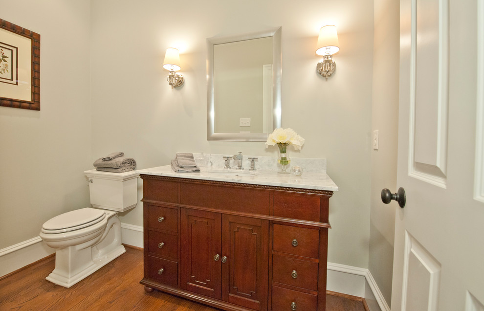 Design ideas for a large traditional powder room in Philadelphia with furniture-like cabinets, medium wood cabinets, a two-piece toilet, grey walls, an undermount sink and marble benchtops.