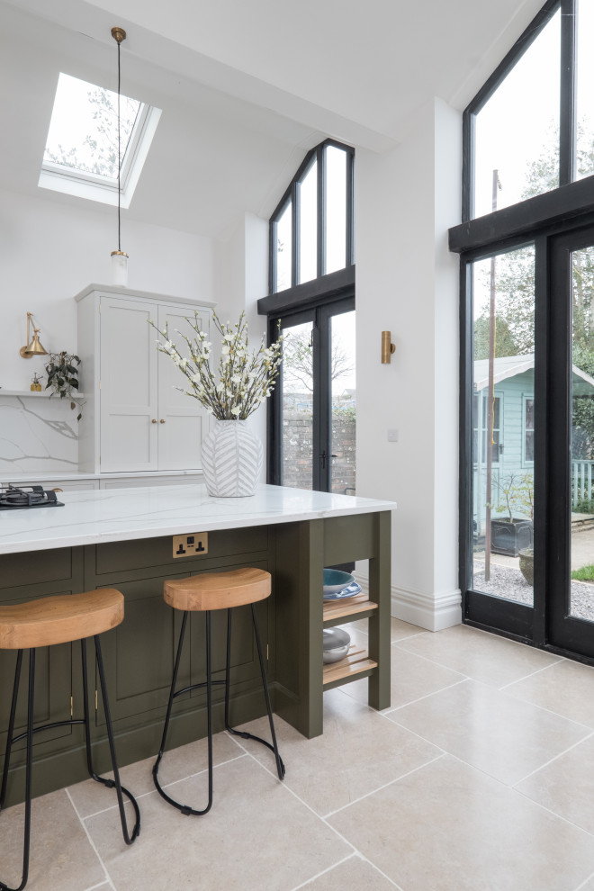 Inspiration for a large classic single-wall open plan kitchen in Cardiff with a belfast sink, shaker cabinets, light wood cabinets, quartz worktops, white splashback, stone slab splashback, stainless steel appliances, porcelain flooring, an island, white worktops, a vaulted ceiling and feature lighting.