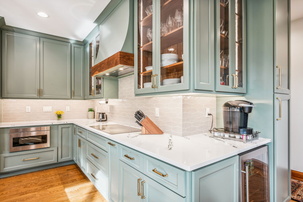 Photo of a large traditional l-shaped open plan kitchen in Columbus with a submerged sink, recessed-panel cabinets, green cabinets, engineered stone countertops, white splashback, ceramic splashback, stainless steel appliances, medium hardwood flooring, an island, white worktops and exposed beams.