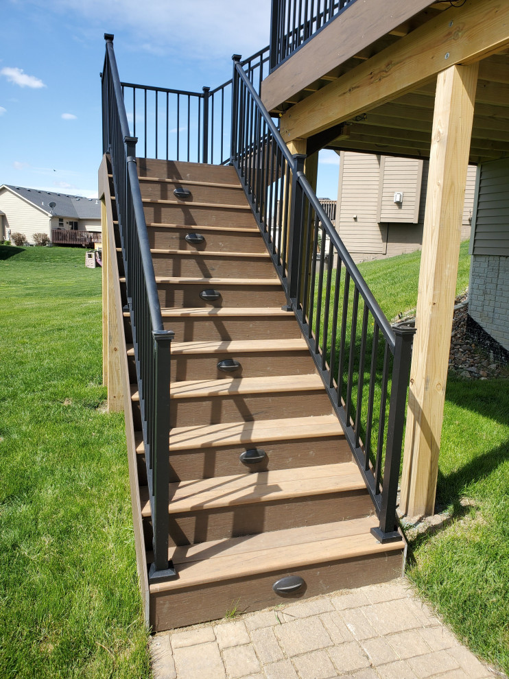 Large backyard second story metal railing deck photo with a roof extension