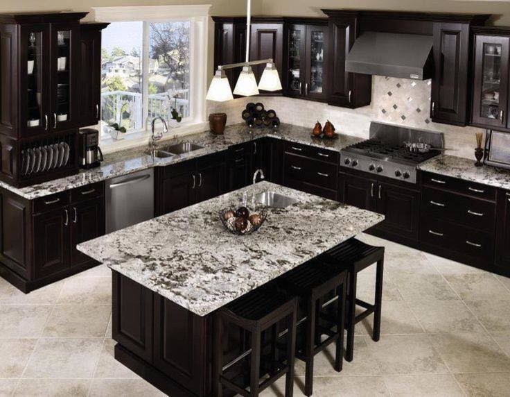 Enclosed kitchen - large transitional l-shaped limestone floor and gray floor enclosed kitchen idea in Austin with a double-bowl sink, glass-front cabinets, dark wood cabinets, granite countertops, gray backsplash, stone tile backsplash, stainless steel appliances and an island