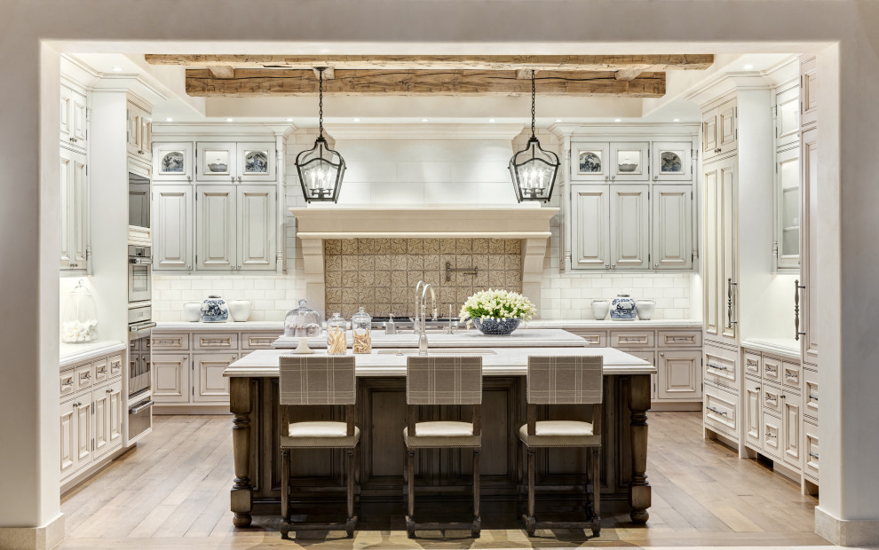 Inspiration for a mediterranean u-shaped kitchen in Phoenix with an undermount sink, raised-panel cabinets, beige cabinets, beige splashback, panelled appliances, medium hardwood floors, with island, brown floor, white benchtop and exposed beam.