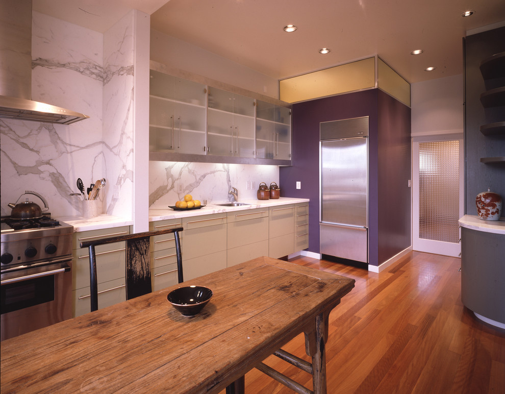 This is an example of a contemporary kitchen in San Francisco with stainless steel appliances, an undermount sink, glass-front cabinets, white cabinets, marble benchtops, white splashback and stone slab splashback.