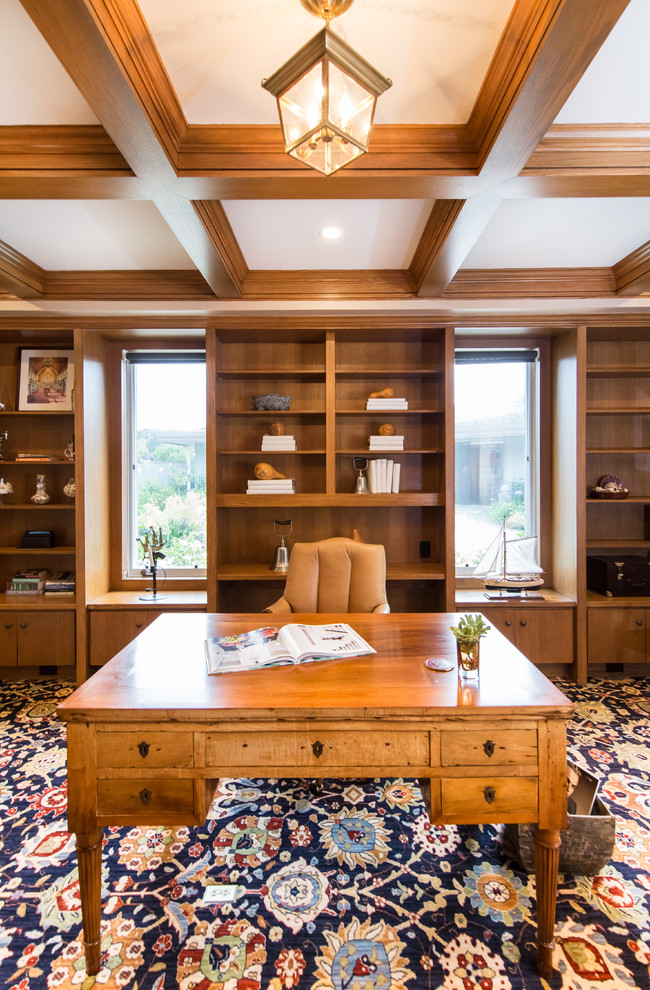 Large transitional home office in Los Angeles with a library, beige walls, carpet, a freestanding desk and blue floor.
