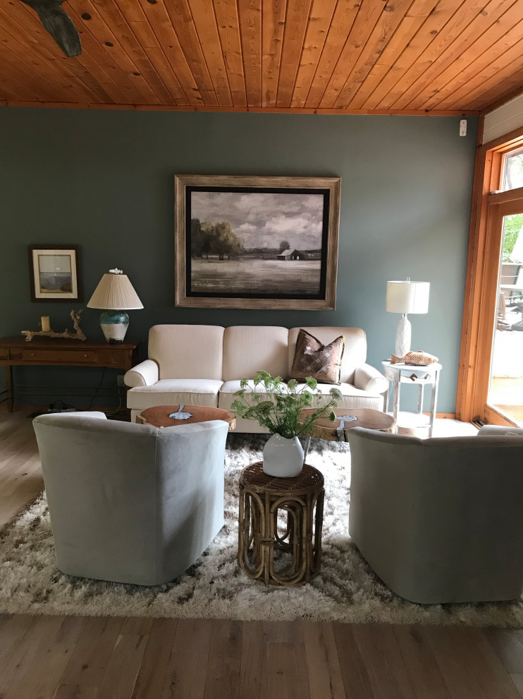 Modelo de salón para visitas abierto costero grande sin televisor con paredes azules, suelo de madera clara, suelo beige y madera