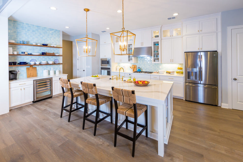 Inspiration for a large beach style l-shaped eat-in kitchen in Jacksonville with shaker cabinets, white cabinets, blue splashback, stainless steel appliances, medium hardwood floors, with island, a farmhouse sink, quartz benchtops and ceramic splashback.