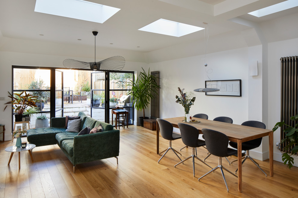 Photo of a mid-sized contemporary open plan dining in London with white walls, light hardwood floors and brown floor.