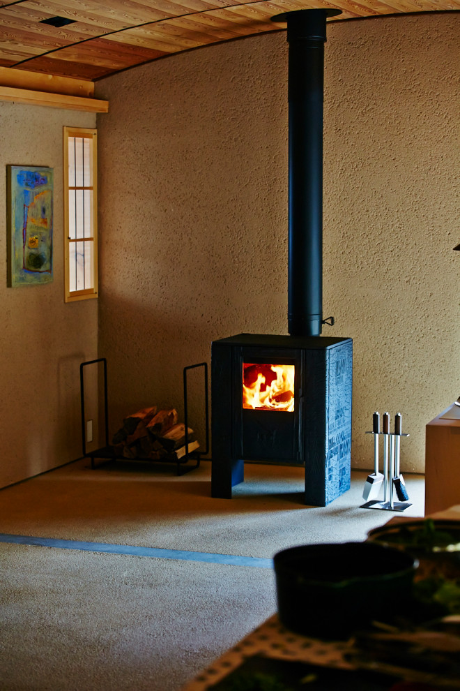This is an example of a modern home office in Other with a wood stove and a concrete fireplace surround.