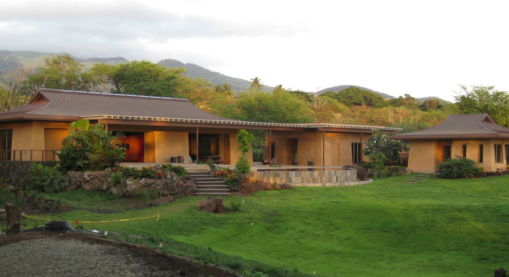 Design ideas for an expansive asian one-storey stucco yellow exterior in Hawaii.