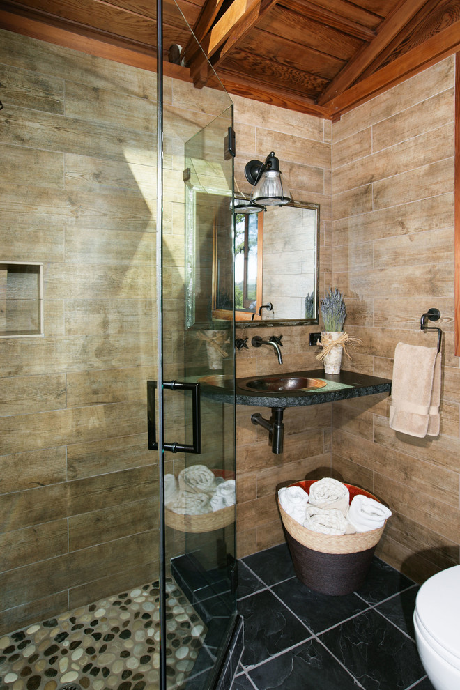 Small transitional 3/4 bathroom in San Francisco with a corner shower, a wall-mount sink, a two-piece toilet, brown walls, porcelain floors, granite benchtops, brown tile, black floor and a hinged shower door.