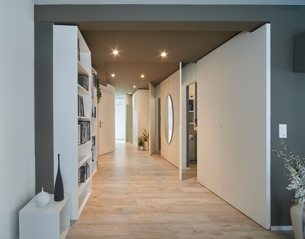 Пример оригинального дизайна: коридор среднего размера в современном стиле с белыми стенами, светлым паркетным полом, многоуровневым потолком и панелями на стенах