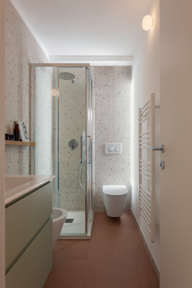 Inredning av ett modernt litet vit vitt badrum med dusch, med släta luckor, gröna skåp, en hörndusch, en toalettstol med separat cisternkåpa, porslinskakel, ett avlångt handfat, rött golv och dusch med skjutdörr