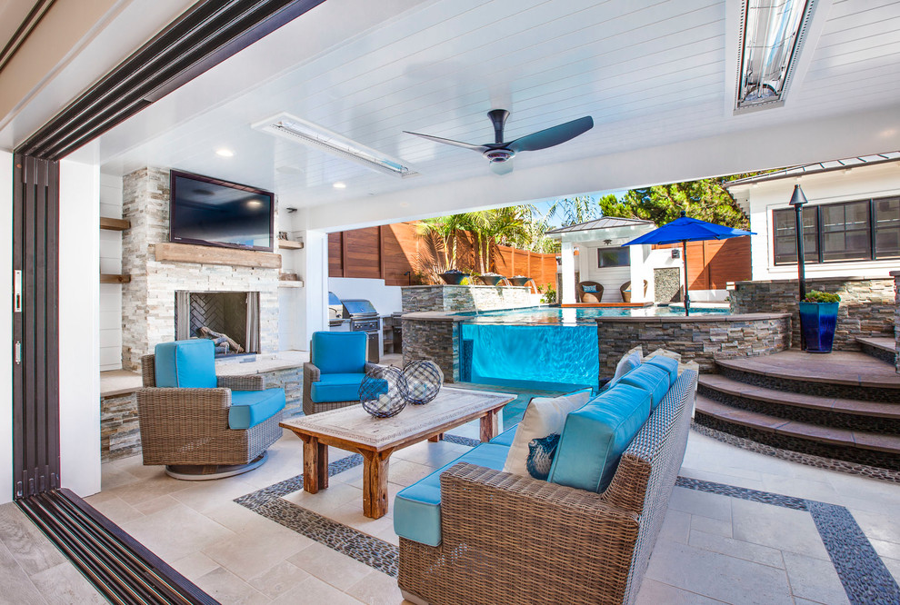 Photo of a beach style backyard patio in Los Angeles with with fireplace, tile and a roof extension.