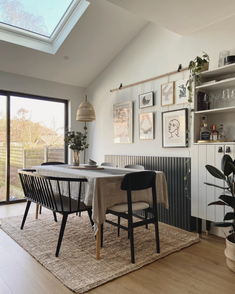 Design ideas for a scandinavian dining room in Manchester with white walls, light hardwood floors, beige floor and vaulted.