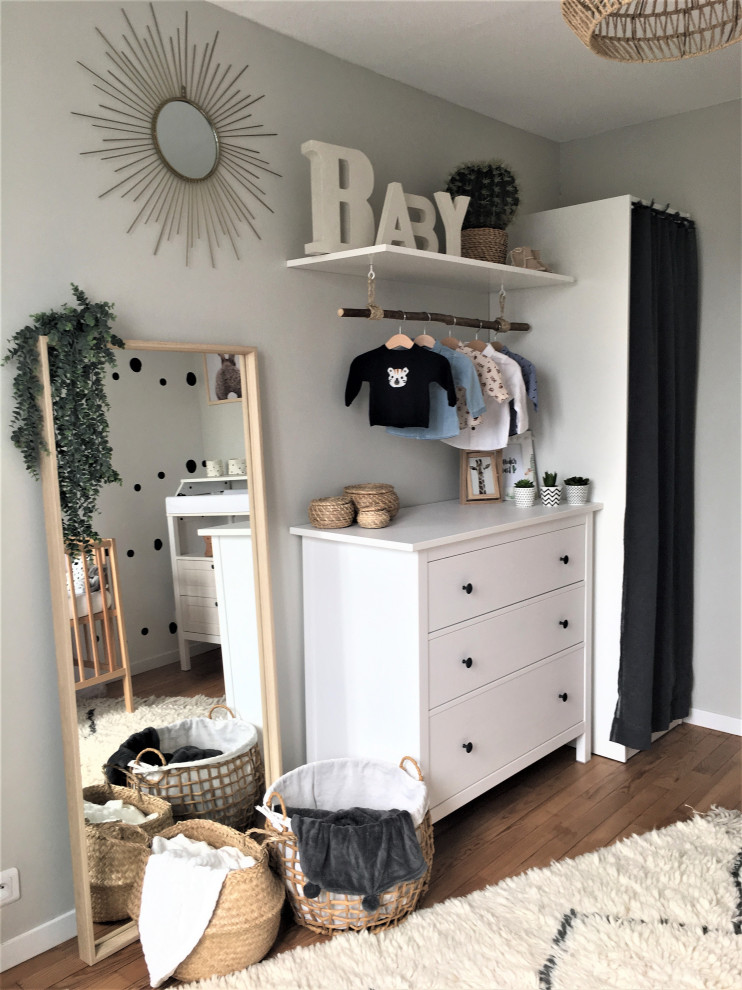 Mittelgroßes Babyzimmer mit braunem Holzboden und Tapetenwänden