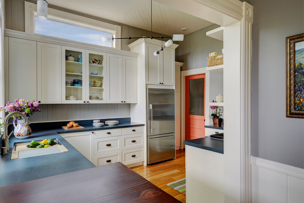 Inspiration for a large transitional u-shaped eat-in kitchen in San Francisco with an undermount sink, white cabinets, grey splashback, timber splashback, stainless steel appliances, medium hardwood floors, no island, brown floor, grey benchtop, shaker cabinets and soapstone benchtops.
