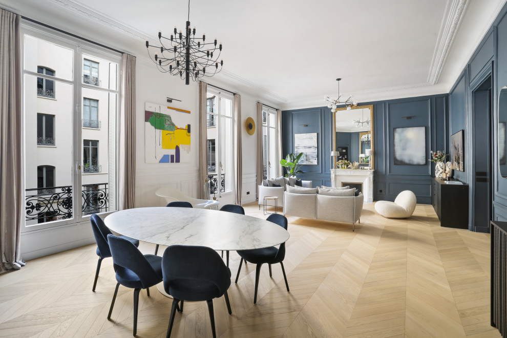 Photo of an expansive contemporary open plan dining room in Paris with blue walls, light hardwood flooring, a plastered fireplace surround, beige floors and wood walls.