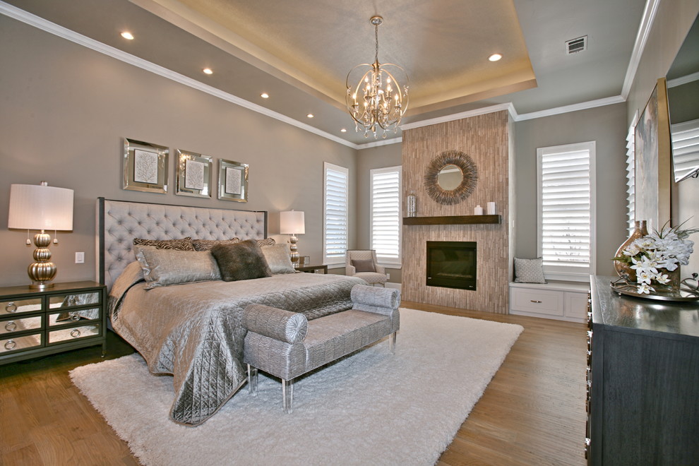 Design ideas for a large contemporary master bedroom in Dallas with beige walls, light hardwood floors, a standard fireplace and a tile fireplace surround.