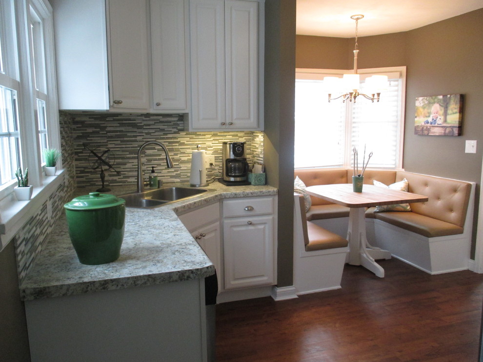 Inspiration for a mid-sized transitional l-shaped medium tone wood floor eat-in kitchen remodel with a drop-in sink, raised-panel cabinets, white cabinets, laminate countertops, gray backsplash, matchstick tile backsplash and stainless steel appliances