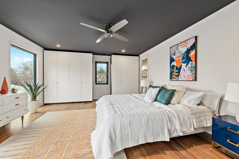 Photo of a large contemporary master bedroom in Charlotte with white walls, medium hardwood floors and brown floor.