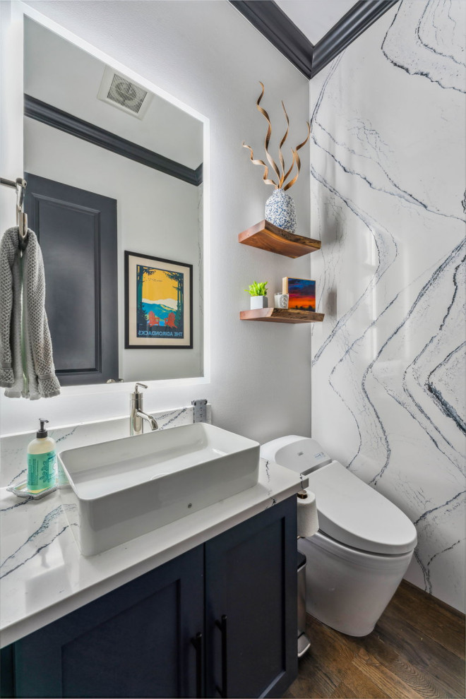 Design ideas for a mid-sized transitional powder room in Columbus with recessed-panel cabinets, blue cabinets, a bidet, white walls, dark hardwood floors, a vessel sink, engineered quartz benchtops, brown floor, white benchtops, a built-in vanity and panelled walls.
