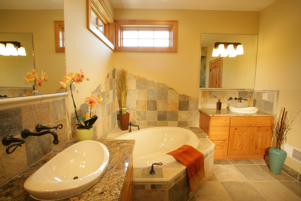 This is an example of a large arts and crafts master bathroom in Other with flat-panel cabinets, medium wood cabinets, a drop-in tub, multi-coloured tile, stone tile, yellow walls, porcelain floors, a drop-in sink, granite benchtops and a curbless shower.