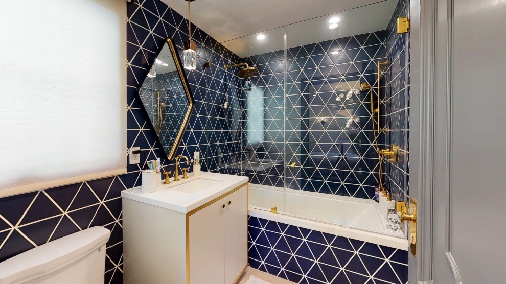 На фото: главная ванная комната среднего размера с плоскими фасадами, белыми фасадами, ванной в нише, душем над ванной, унитазом-моноблоком, синей плиткой, керамической плиткой, синими стенами, полом из цементной плитки, врезной раковиной, мраморной столешницей, белым полом, душем с распашными дверями, белой столешницей, тумбой под одну раковину и встроенной тумбой с