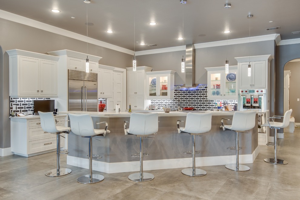 Transitional l-shaped open plan kitchen in Dallas with shaker cabinets, white cabinets, black splashback, stainless steel appliances, concrete floors, with island and grey floor.