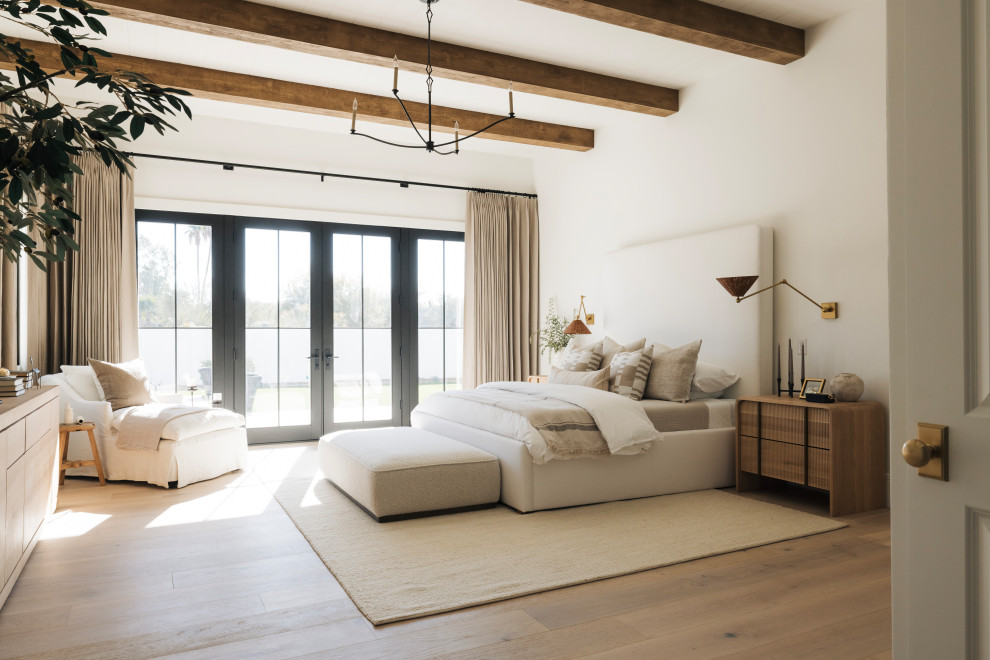 Foto di una camera da letto tradizionale con pareti bianche, pavimento in legno massello medio, pavimento marrone e travi a vista