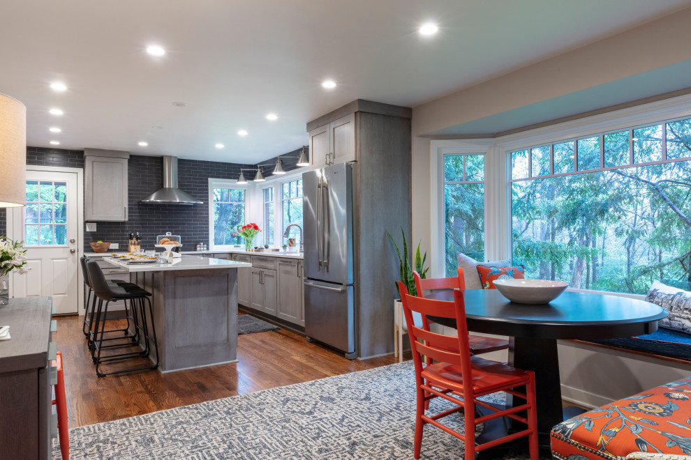 Trendy u-shaped medium tone wood floor and brown floor eat-in kitchen photo with shaker cabinets, gray cabinets, quartz countertops, gray backsplash, ceramic backsplash, stainless steel appliances, an island, gray countertops and an undermount sink